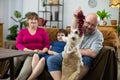 The father shows the grape to the dog and the whole family smiles.