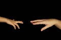 Mother and son hands reach for each other. Isolated women and children palms on a black background. Concept of family relations.