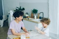 Mother and son having fun with flour cooking home-made cookies in kitchen