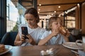 Mother and son having lunch in sidewalk restaurant. Mom and son eat a croissant in a cafe. Woman photographing food Royalty Free Stock Photo