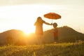 A mother and son holding umbrella and playing outdoors at sunset Royalty Free Stock Photo