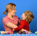 Mother and son hug on blue. Woman and little boy