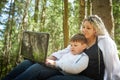 Mother and son with a laptops in forest in summer. Fat young smart teenage boy and woman working with modern IT Royalty Free Stock Photo