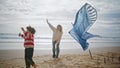 Mother son launching kite on windy ocean shore. Cheerful woman helping child Royalty Free Stock Photo