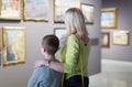 Mother and son looking at paintings in halls of museum Royalty Free Stock Photo