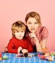 Mother and son making Easter decorations. Woman and child with happy faces on pink background. Mom and boy spend time Royalty Free Stock Photo