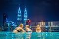 Mother and son in outdoor swimming pool with city view at night Royalty Free Stock Photo