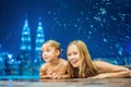 Mother and son in outdoor swimming pool with city view at night Royalty Free Stock Photo