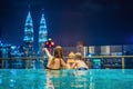 Mother and son in outdoor swimming pool with city view at night Royalty Free Stock Photo