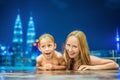 Mother and son in outdoor swimming pool with city view at night Royalty Free Stock Photo