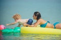 Mother with son play ball in water. Happy family on Caribbean sea. Pineapple inflatable or air mattress. Summer vacation Royalty Free Stock Photo