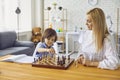 Mother and son play chess at the table at home.Happy family with parent and child enjoying board game at home Royalty Free Stock Photo