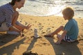 mother and son play with stones building a tower on the beach on a sunny day Royalty Free Stock Photo