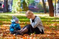 Mother and son are played in the fallen leaves for a walk in the city park Royalty Free Stock Photo