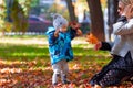 Mother and son are played in the fallen leaves for a walk in the city park Royalty Free Stock Photo