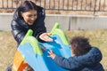 Mother - son relationship. Outdoor shot of a young caucasian black-haired mum encouraging her biracial toddler boy to Royalty Free Stock Photo