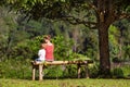 Mother with son sit on bench under tree