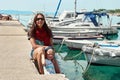 Mother and son sit on port pier near moored on water boats Royalty Free Stock Photo