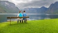 Mother and son sitting on a bench looking at the fjord