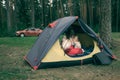 Mother and son sitting in camping tent, wrapped in wool blanket, car stay near in woods. Family weekend outdoor, local travel on Royalty Free Stock Photo