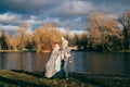 Mother and son sitting near lake in autumn park on sunset and looking away. Family having fun, hugging, laughing, relaxing, enjoy Royalty Free Stock Photo