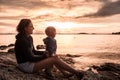 Mother and son sitting on a rocky beach, having fun