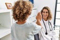 Mother and son smiling confident high five raised up hands at clinic