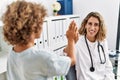 Mother and son smiling confident high five raised up hands at clinic