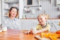 Mother and son are smiling while having a breakfast in kitchen. Mom is pouring milk into glass Royalty Free Stock Photo