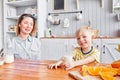 Mother and son are smiling while having a breakfast in kitchen. Mom is pouring milk into glass Royalty Free Stock Photo