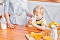 The boy drinks milk from a glass. Mother and son are smiling while having a breakfast in kitchen. Mom is pouring milk Royalty Free Stock Photo