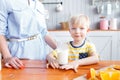 Mother and son are smiling while having a breakfast in kitchen. Mom is pouring milk into glass Royalty Free Stock Photo