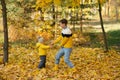 Mother and son smiling and playing in autumn park among yellow leaves Royalty Free Stock Photo