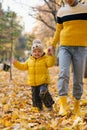 Mother and son smiling and playing in autumn park among yellow leaves Royalty Free Stock Photo