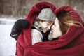 Mother and son snuggling under heart shaped blanket outside in the snow Royalty Free Stock Photo