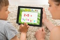 Mother And Son Solving Math Problem On Digital Tablet