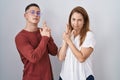 Mother and son standing together over isolated background holding symbolic gun with hand gesture, playing killing shooting Royalty Free Stock Photo