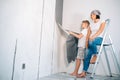 Mother and son take off wallpapers from wall and prepare room for renovation