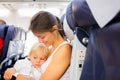 Mother and son, toddler boy, sitting together in airplane furing flight for a family holiday