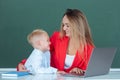 Mother and son together using computer laptop. Elementary school classroom. Teacher and schoolchild pupil in class Royalty Free Stock Photo