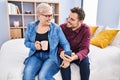Mother and son using smartphone drinking coffee sitting on bed at bedroom Royalty Free Stock Photo