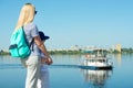 Mother and son walk along the promenade and look at the ship floating on the river. Royalty Free Stock Photo