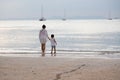 Mother and son are walking on the beach and look at the water and yachts in the sea