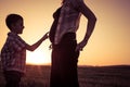 Mother and son walking on the field at the sunset time. Royalty Free Stock Photo