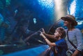 Mother and son walking in indoor huge aquarium tunnel, enjoying a underwater sea inhabitants, showing an interesting to each other