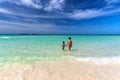 Mother and son walking towards white sandy Cuban beach in Cayo Coco