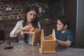 Little boy and his beautiful mother crafting a wooden birdhouse at home