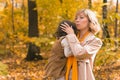 Mother soothes her crying blonde daughter. Mom holds sadness baby in her arms in autumn nature. Royalty Free Stock Photo