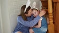 a mother soothes her crying daughter on the wooden stairs of the house.