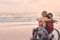 Mother and special child on wheelchair on the sea beach with sunset Royalty Free Stock Photo